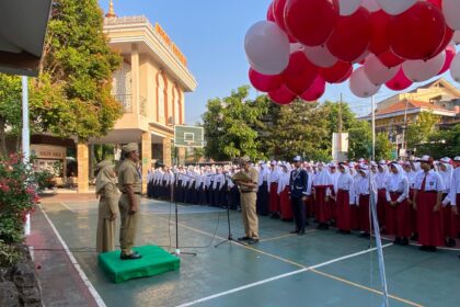 Kepala Dinas Pendidikan Kepemudaan dan Olahraga Kudus Harjuna Widada mengalungkan tanda peserta kepada perwakilan murid baru kelas VII.