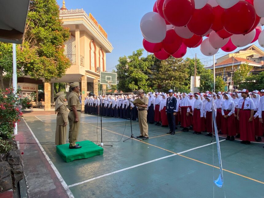 Kepala Dinas Pendidikan Kepemudaan dan Olahraga Kudus Harjuna Widada mengalungkan tanda peserta kepada perwakilan murid baru kelas VII.